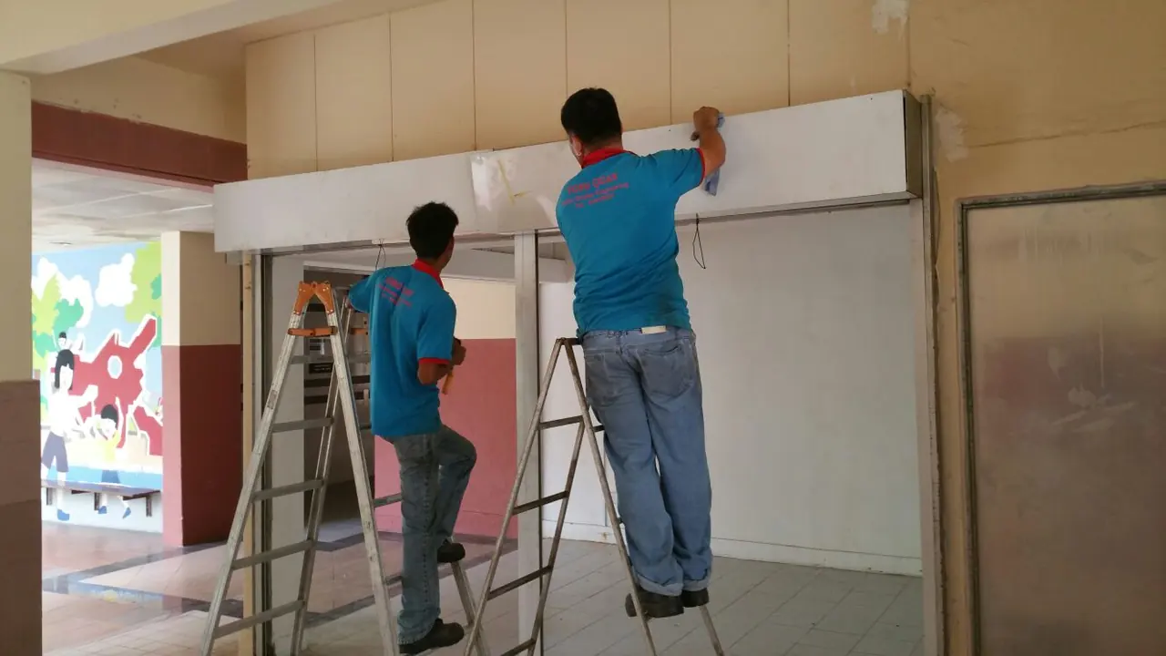 Yong Quan installers servicing a roller shutter