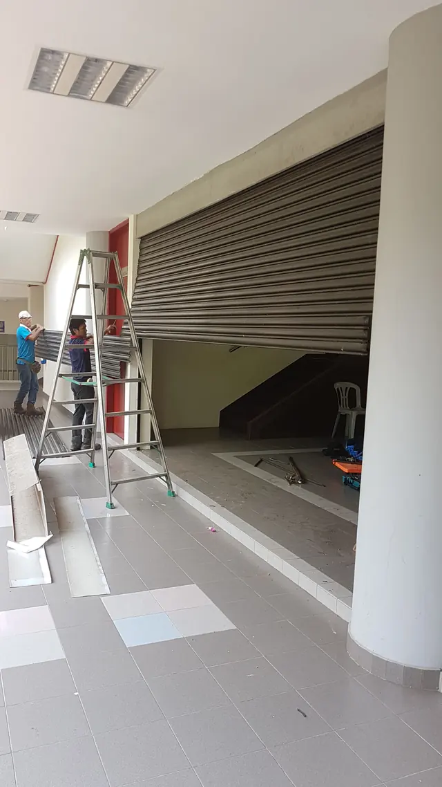 Installers replacing a roller shutter curtain